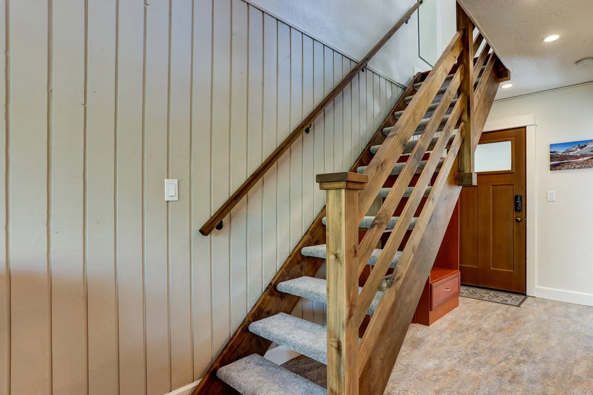 This image provides a glimpse into the entryway of Rabbit’s Rest, featuring a welcoming staircase, front door, and warm wall paneling. The inviting scene suggests the start or end of a day spent exploring Bend’s local culture, seamlessly connecting the interior retreat to the broader neighborhood experience.
